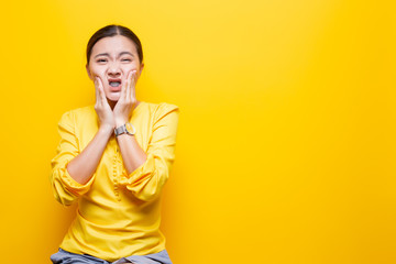 Woman has toothache isolated over yellow background