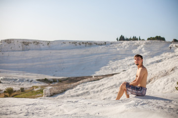 Natural travertine pools and terraces in Pamukkale. Cotton castle in southwestern Turkey, man sitting in natural pool. A man swims in the pool of thermal springs and travertine Pamukkale