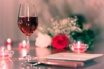 glass of red wine and roses on restaurant table