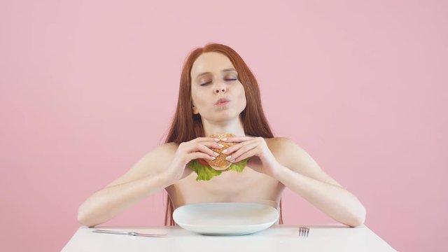 Happy skinny girl breaks the diet and eats a Burger. Violation of diet. Anorexia.