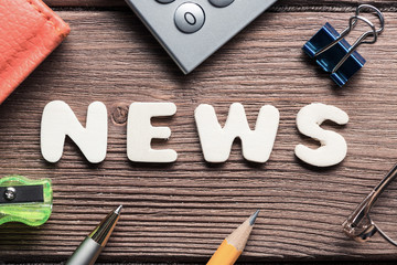 News word on wooden table and office stationary around