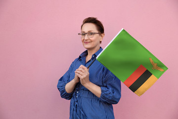 Zambia flag. Woman holding Zambia flag. Nice portrait of middle aged lady 40 50 years old holding a...
