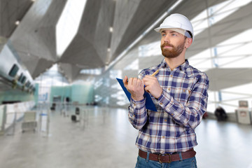 Young male engineer with helmet holding blueprints