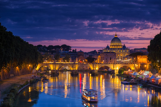 Night view of old Sant' Angelo Bridge and St. Peter's cathedral in Vatican City Rome Italy.