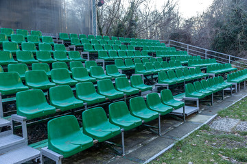 Empty old plastic chairs in the stands of the summer theater. Many empty seats for spectators in the stands of the amphitheater. Empty plastic chairs, seating for the audience. Plastic pot