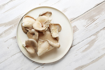 Surowe boczniaki. Grzyby na talerzu na białym blacie. © foodandcook