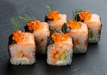 Sushi roll with salmon and caviar on black background