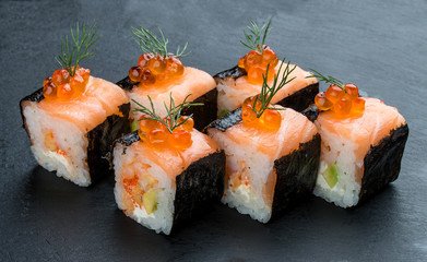 Sushi roll with salmon and caviar on black background