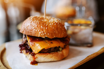 Close up of delicious burger on the wooden plate. - obrazy, fototapety, plakaty