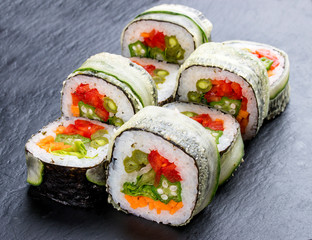 Sushi roll with vegetables on black background. Vegetarian dish.