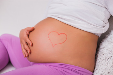 Close up of pregnant woman's stomach with heart drawing.