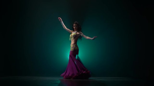 Traditional oriental belly dancer girl dancing on smoke background