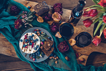 Camembert cheese with blueberries, bread, nuts and red wine decorated with flowers