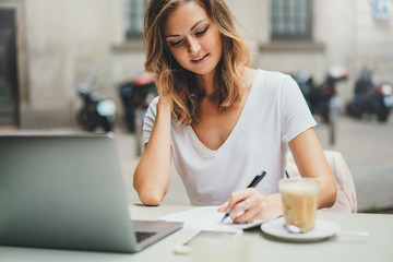Beautiful young freelancer woman using laptop computer sitting at cafe table. Happy smiling girl...