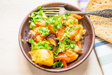 Roast vegetables on a rustic plate, standing on a light wooden table - a healthy organic dish.
