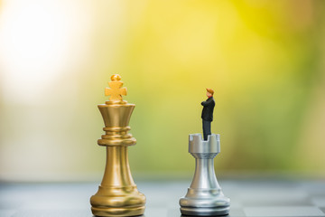 Business decision making concept. Miniature people : small businessman figure standing and walking on chessboard with chess pieces