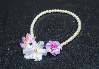 pearl necklace with violet flowers on a brocade black background
