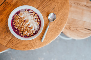 Beautiful blueberry banana smoothie bowl with a spoon on wooden table. Healthy breakfast concept.