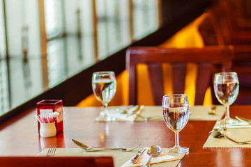 Glasses, spoon, frog, knife, napkin and plates on table setting for meeting and celebrating decoration.