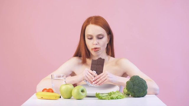 Happy anorexic girl greedily eats chocolate. Violation of diet. Poor diet. Anorexia.