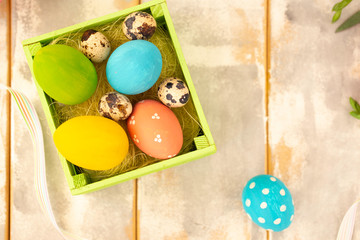 Easter background with Easter eggs and quail on a wooden white and gray table. Top view with copy space.