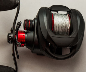 Close up of baitcasting reel loaded with braided mainline isolated against a white background