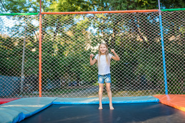 Happy funny girl jumping on trampoline