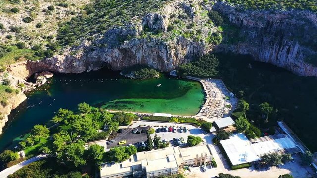 Aerial drone, bird's eye video from iconic lake Vouliagmeni famous for healing abilities and Vouliagmeni Peninsula at the background, Athens riviera, Attica, Greece