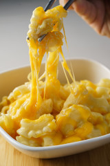 man eating mac and melted cheese with metal chopsticks