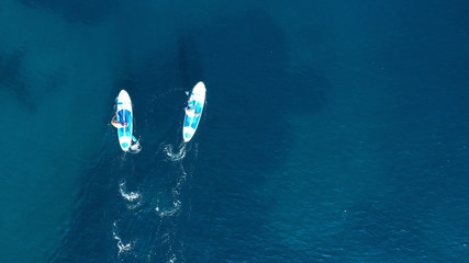 Aerial drone bird's eye view of 2 men exercising sup board in turquoise tropical clear waters