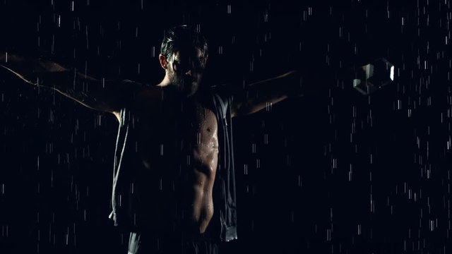 Athletic man working out in the rain. Slow Motion.