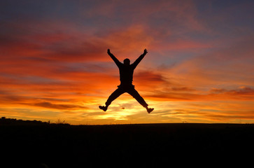 A man is jumping on the background of an incredible beautiful sunset.