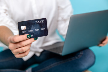 Photo of handsome young woman with black credit card near the computer