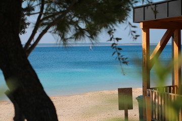 View from the beach to the azure sea through trees.