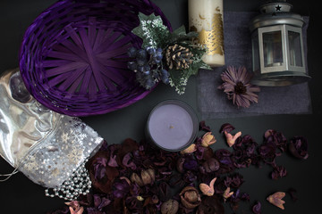 Purple color flowers , silver chain near candle on a black background , top view