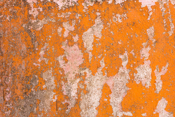 peeling orange paint from light gray concrete wall with black spots of dirt and mold. rough surface texture