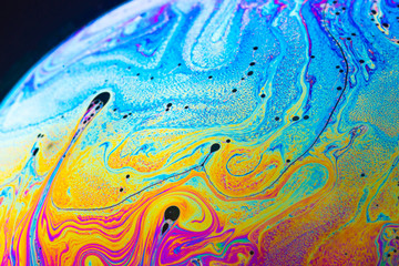 Rainbow soap bubble on a dark background.