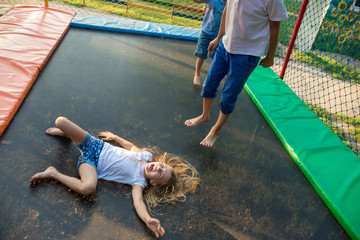 Two boys  jump on trampoline and girl lays and enjoy