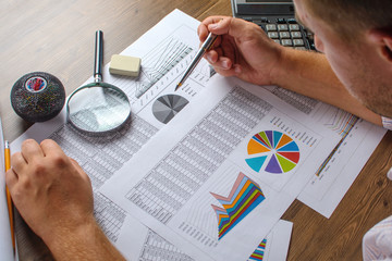 Business analysis - calculator, sheet, graphs (business report) and analyst hand, top view