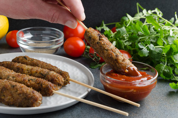 Man dipes tasty lule kebab into the satsebeli sauce.Process of eating meat food