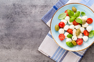 Delicious caprese salad with ripe cherry tomatoes and mini mozzarella cheese balls with fresh basil leaves.