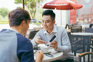 Checking stocks. Two business partners working on the laptop smiling cheerfully on a meeting at the local cafe - Image