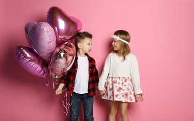 Little boy and girl kids with pastel color balloons for valentines day or birthday in kindergarten