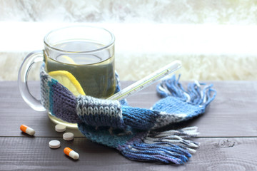 Fototapeta na wymiar warming recipes for colds. pills and capsules on the table against the background of drinking with a lemon and a thermometer when it is winter