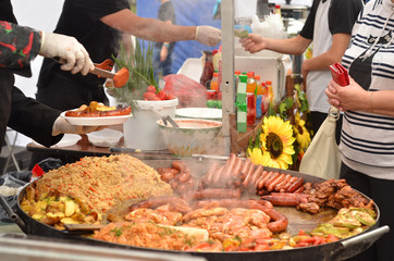 People buying food.Decomposed street food on a large metal tray.