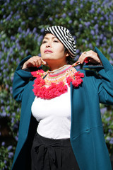 Femme écharpe rouge et beret devant un massif de fleurs bleues