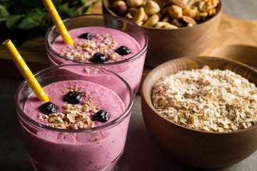Glasses of berry smoothie with nuts, mint, blueberry, raspberry, and yogurt on wooden table. Weight loss and diet concept. 