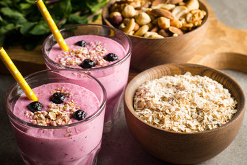 Glasses of berry smoothie with nuts, mint, blueberry, raspberry, and yogurt on wooden table. Weight loss and diet concept. 