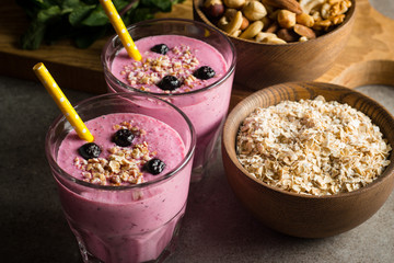 Glasses of berry smoothie with nuts, mint, blueberry, raspberry, and yogurt on wooden table. Weight loss and diet concept. 