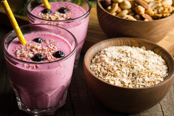 Glasses of berry smoothie with nuts, mint, blueberry, raspberry, and yogurt on wooden table. Weight loss and diet concept. 